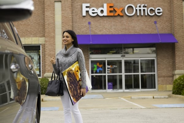 woman walking out of FedEx Office holding printed photo canvas