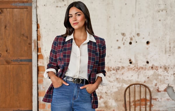 Woman is wearing an ivory button down blouse and a red plaid blazer.