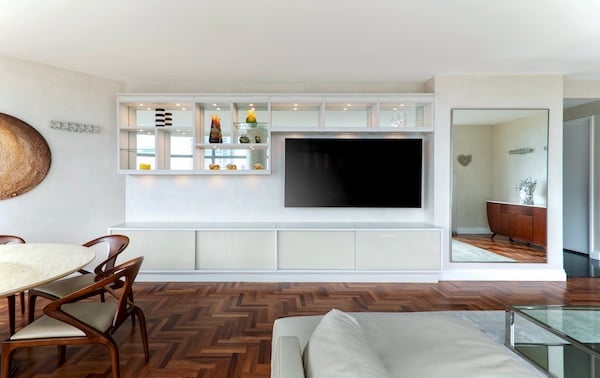 Custom California Closets living room wall unit featuring a built-in white media center with integrated shelving, glass display cabinets, and a wall-mounted flat-screen TV above sleek lower storage cabinets