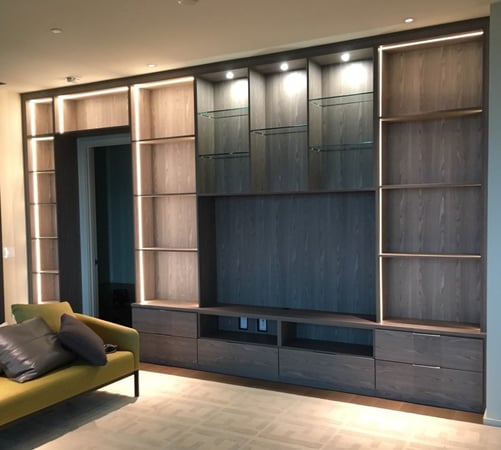 Dark colored media center and bookshelf includes accent lighting, glass shelves and cubbies in a lighter finish.