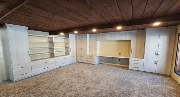 Custom home office in basement with built-in custom cabinets, bookshelf with cabinets, and integrated workspace storage. West Bloomfield, Michigan