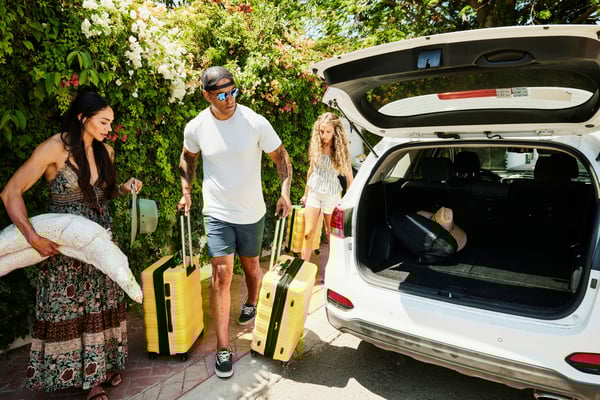 Friends unloading luggage from trunk of car