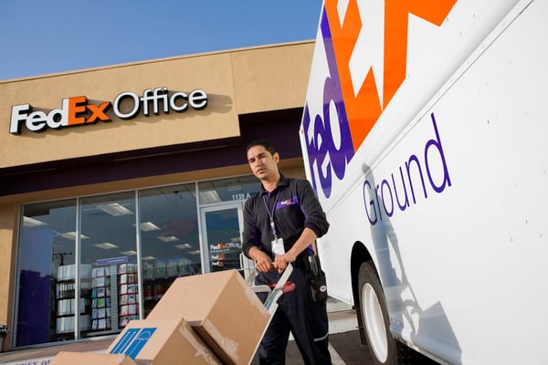 FedEx courier and FedEx Ground van in front of FedEx Office