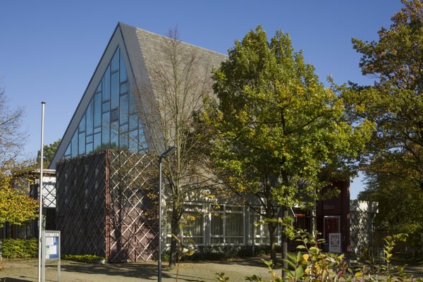 Das moderne Kirchengebäude umringt von Bäumen.
