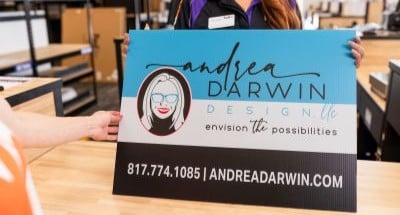 FedEx Office team member presenting a custom printed yard sign for a local business.