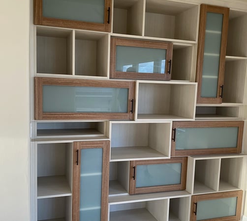 A bookshelf with stacked boxes of varied depths and Shaker doors with semi-opaque glass creates an interesting composition.