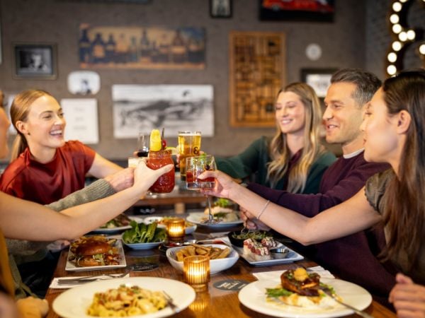 A large group of people   dining and cheering with ththeir drinks