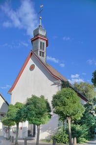Außenansicht der Kirche Undenheim. Das Gebäude ist weiß und auffällig ist der herausragende Kirchturm.