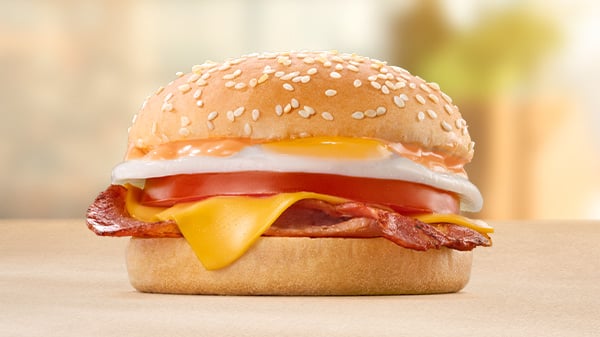The Bacon, Egg, Cheese & Tomato Bun on a brown surface with a blurred background