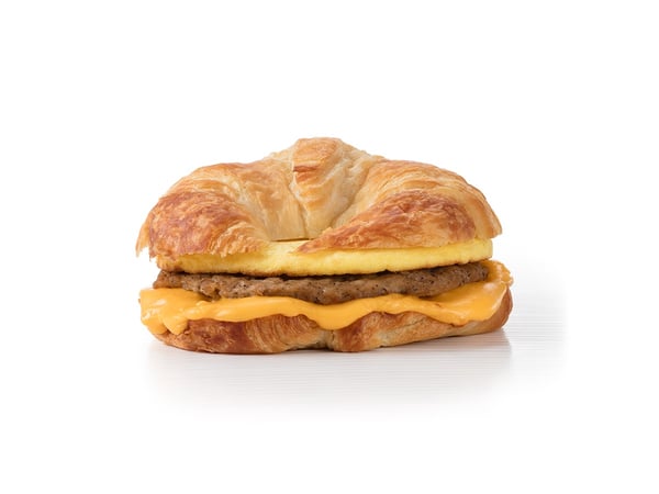 A breakfast croissant sandwich with egg and sausage.