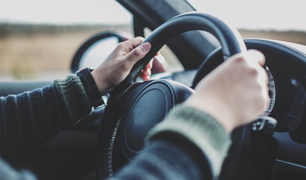 Man with hands on steering wheel.