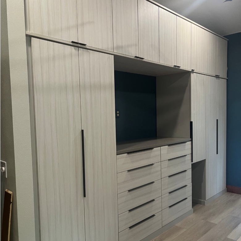 Custom master bedroom wardrobe in Tuscan Moon and Sunset Mist finishes with graphite finger-pull hardware in varying lengths, designed for hanging garments, shoes, jewelry storage, and a built-in opening for a cat bed.