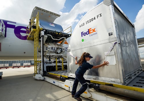 Gran carga de FedEx siendo cargada en avión por la empleada