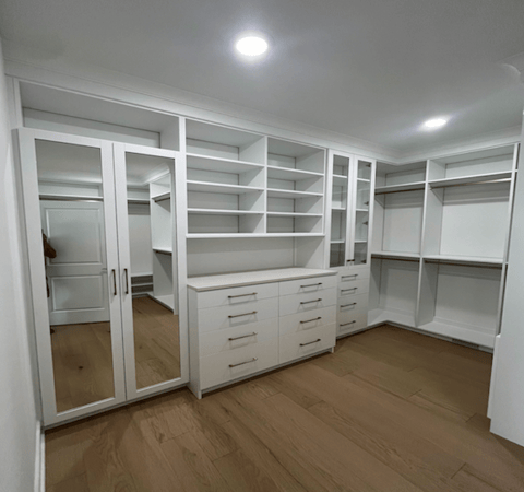 Custom Walk-in closet with white wood, glass cabinets, drawers, and hanging space