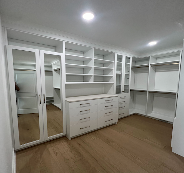Custom Walk-in closet with white wood, glass cabinets, drawers, and hanging space
