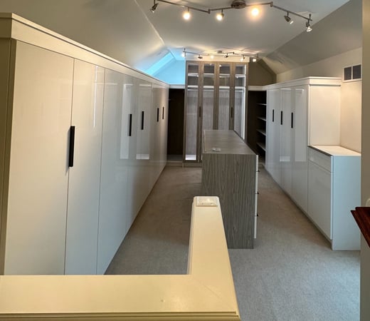 Walk in closet with roof line, glass doors, an island and high gloss doors