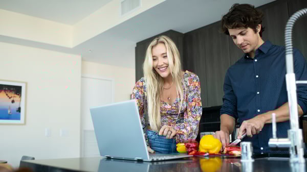 Pareja frente a una computadora portátil en la cocina en Portland