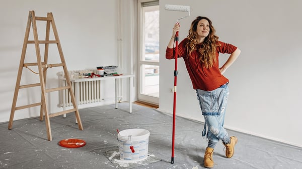 Woman with a paint roller in a room under construction