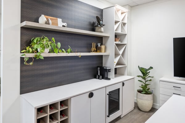 Custom beverage bar with different wine rack styles in white finish with dark backing and maple accents.