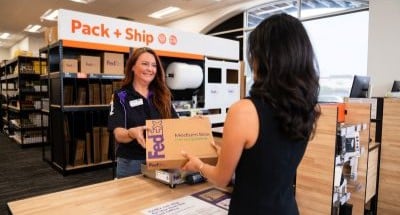 Customer dropping off a FedEx package with a team member at the Pack & Ship counter inside FedEx Office.