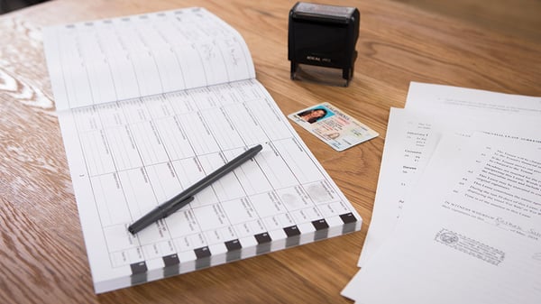 documents next to a notary stamp and notary logbook