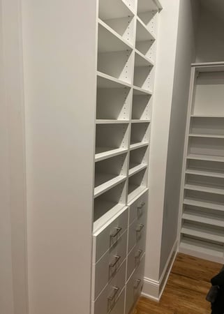 A white walk-in closet with shelves and drawers for efficient storage.