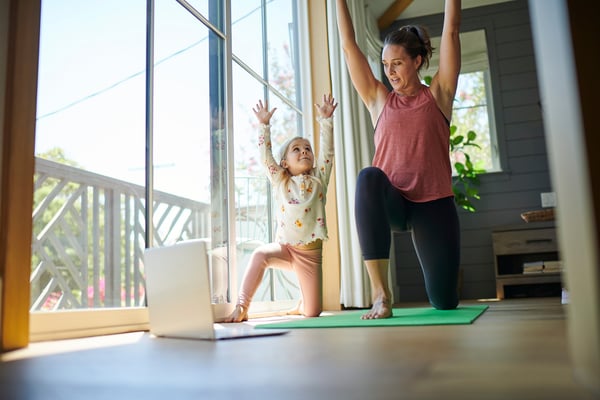 Madre e hija haciendo yoga mirando una laptop