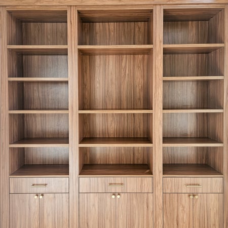 Library in a reddish brown finish with open shelving, drawers, and closed cabinets.