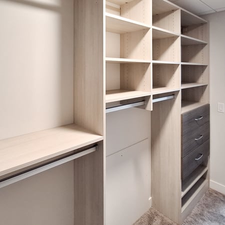 Walk-in closet designed in a light wood grain finish with contrasting drawer fronts. Open shelving, double hanging, and drawers provide a lot of storage.