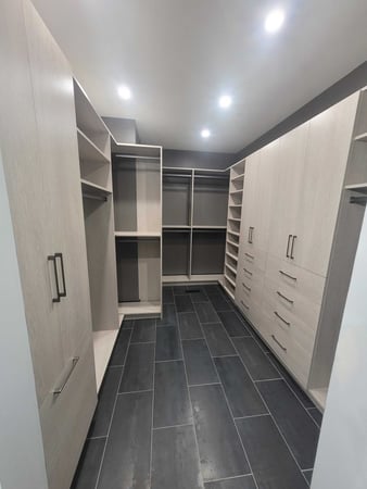 Custom Walk-in closet with black tile floor and light beige color boards