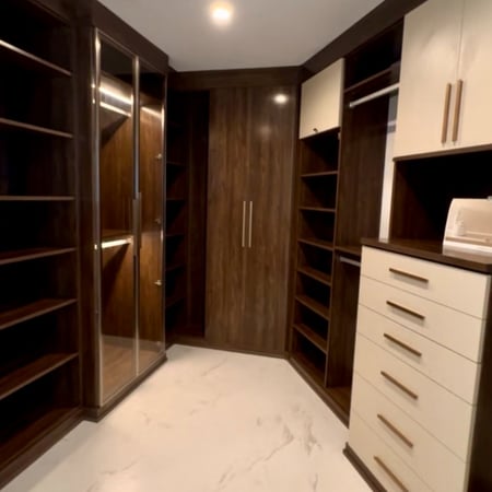 Master closet in Sorrento finish with Stone drawer faces, featuring Element Design aluminum doors in brushed aluminum with bronze glass inserts and Paxton handles in gold for a modern, luxurious storage solution.