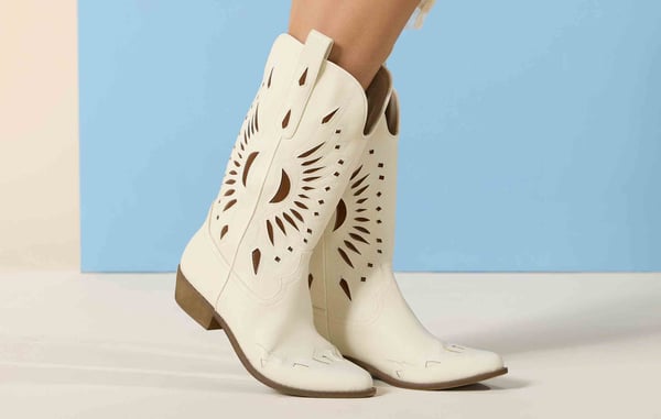 Woman is wearing white cut-out western boots.