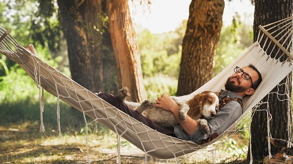 A man and dog sleeping on a hammock.