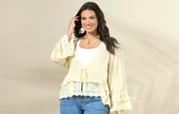 Woman is wearing a yellow plus size long sleeve kimono and plus size jean shorts from Cato Fashions.