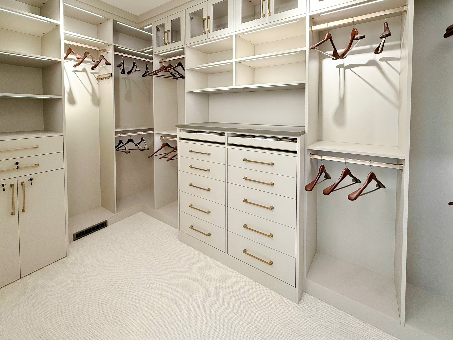 Walk in closet with double hang, long hang, a bank drawers, closed storage and lighting.