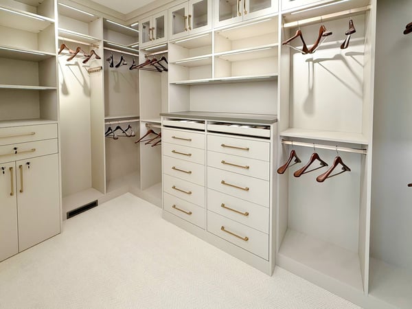 Walk in closet with double hang, long hang, a bank drawers, closed storage and lighting.