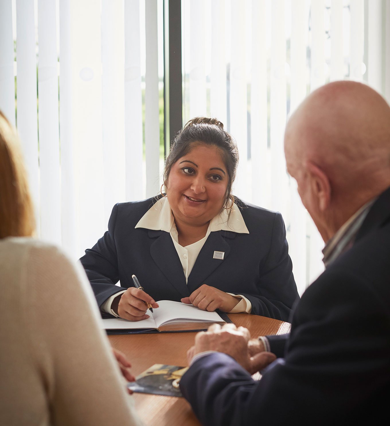 A female funeral arranger sits with a family to arrange a funeral.