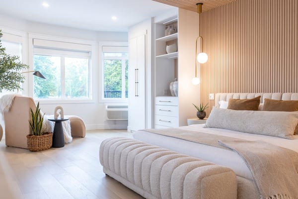 Modern hotelroom with slat walls, kingsize bed, comfortable chair and built in white closets with drawers