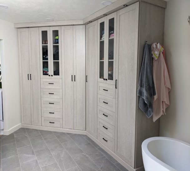 His and hers fully enclosed wardrobe units in bathroom, utilizing lighting, top trim, shaker doors and glass