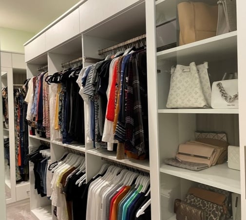 Large walk-in closet with built in double-hang shelving, drawers and tall side cabinets.