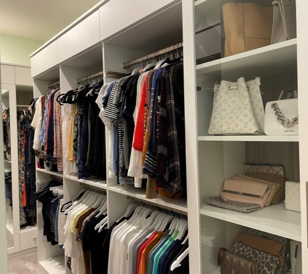 Large walk-in closet with built in double-hang shelving, drawers and tall side cabinets.