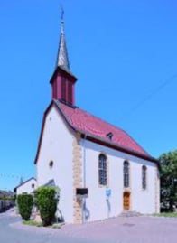Außenansicht der Kirche in Bubenheim. Das Gebäude ist in weiß gehalten und das Dach ist rot.