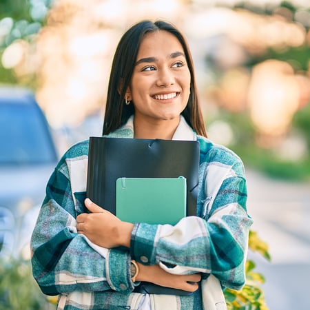 A smiling young woman holding notebooks