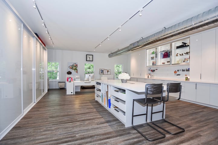 Commercial office with all white acrylic doors and drawers, white glass and large island for workspace.