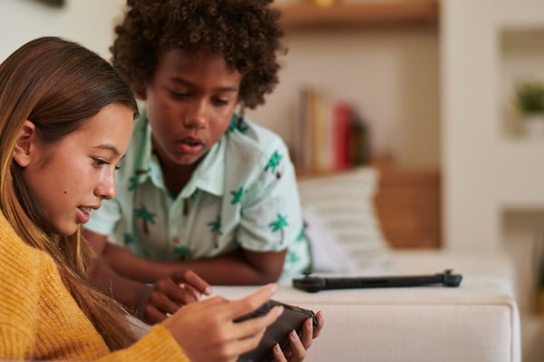 niño y niña jugando en un dispositivo