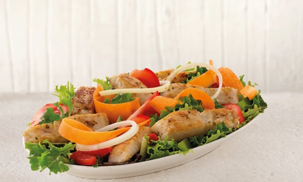 Hake salad with strips of grilled hake, lettuce, carrot, tomato, and onion