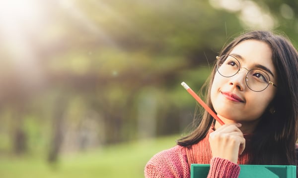 筆記用具をもって物思いにふける女性