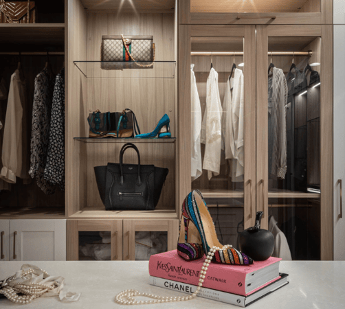 Img 4 California Closets Westchester County New York Two Toned White and Beige Large Walk-in Luxury Closet with Glass Shelving, Glass Doors, Lighting, and a Custom Center Island with Custom Jewelry Drawers