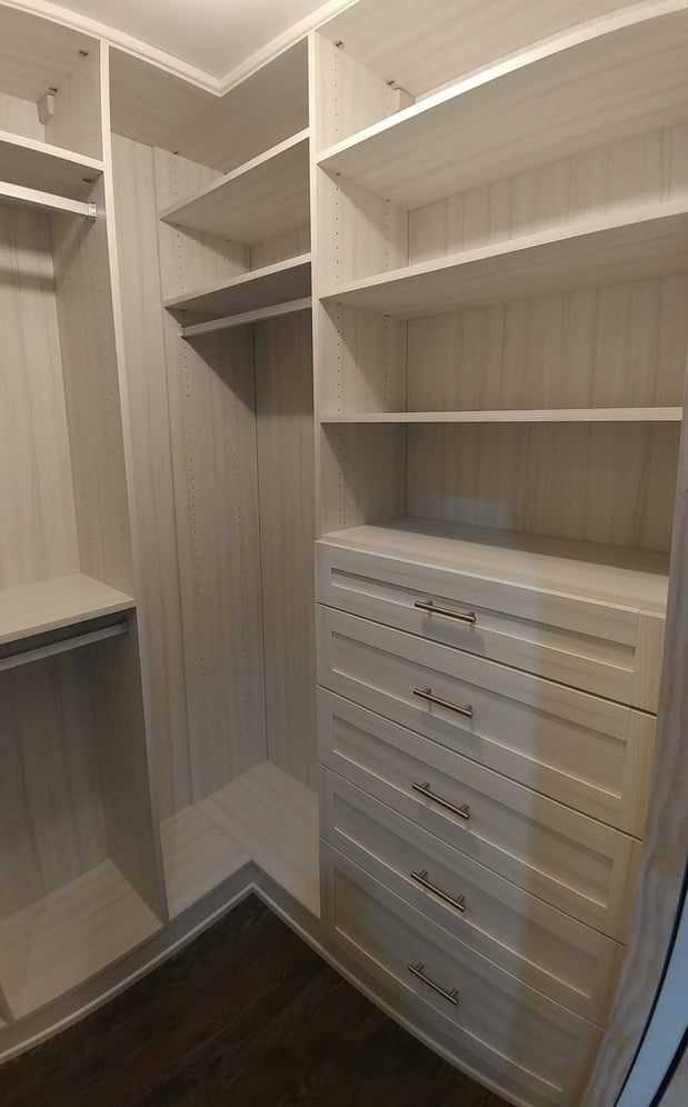 White walk-in closet with shelving, drawers, and hanging rods.