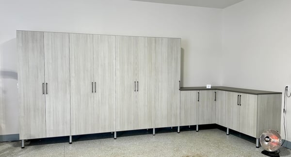 Custom garage storage featuring garage cabinets, garage organization systems, and built-in storage solutions. This organized garage design combines enclosed cabinetry and workspace areas to maximize storage and improve functionality. South Lyon, Michigan.